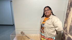 Photo of Monica Jo Raphael next to a rattle she made with porcupine quills