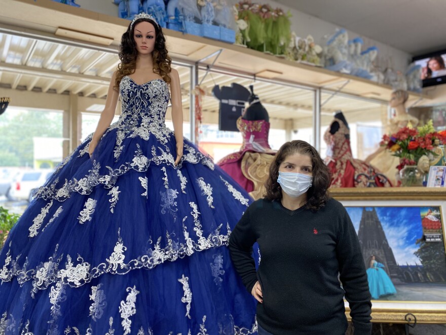 Yolanda Plascencia Sánchez, owner of Yolanda's Creations, a store dedicated to selling dresses and decorations for traditionally Latino events, poses next to one of the many quinceañera dresses in her store.