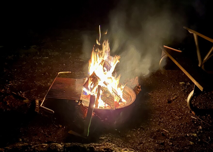 A campfire burns inside a fire ring at night