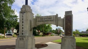 A concrete "welcome" city arch spans a sidewalk