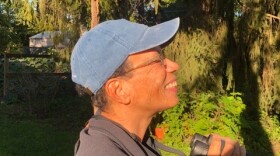 April Campbell, founder of "BIPOC Birders of Michigan", admires nature as she holds her binoculars.