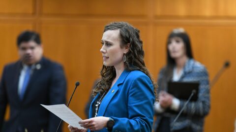 Woman stands at mic and speaks