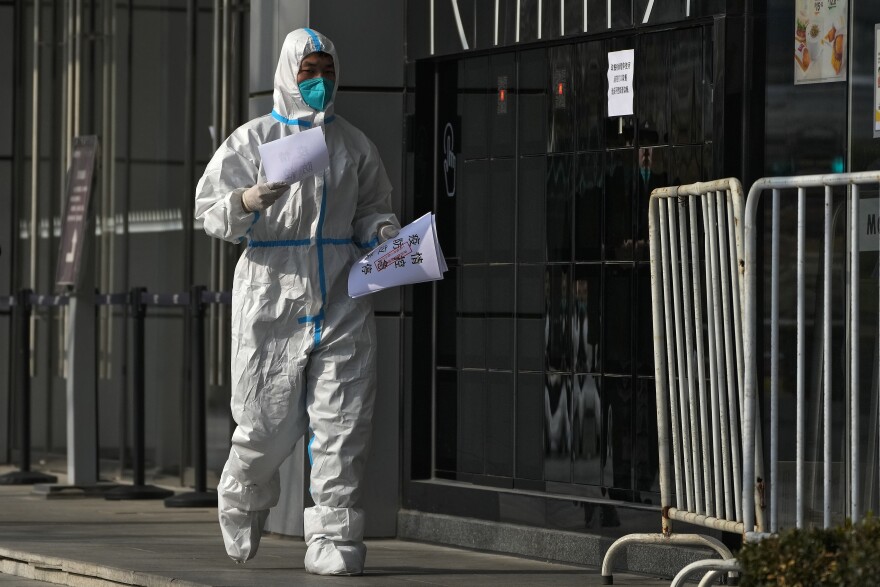 A worker in protective gear places closure notices on the barricaded restaurants at a shuttered commercial office building as part of COVID-19 controls in Beijing, Tuesday, Nov. 22, 2022. Anti-virus controls that are confining millions of Chinese families to their homes and shut shops and offices are spurring fears already weak global business and trade might suffer. (AP Photo/Andy Wong)