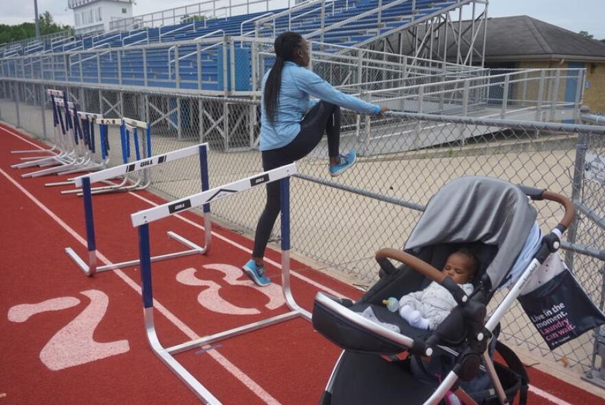 Dawn Harper-Nelson stretches during a training session at Belleville West High School as her daughter, Harper, naps nearby. 