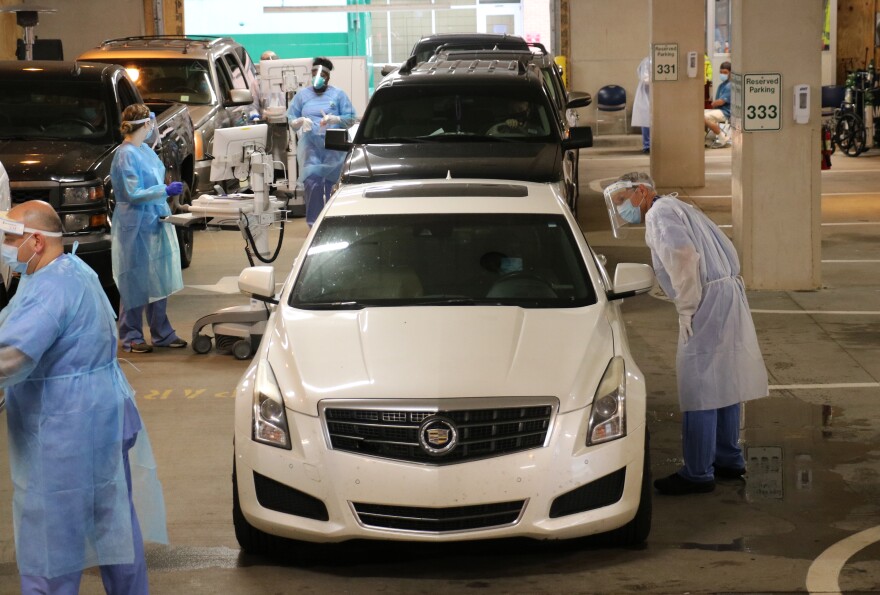 Healthcare workers attend to people being tested at UAMS' drive-thru triage location.