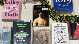 Photos of books with yellow and black caution tape over them.