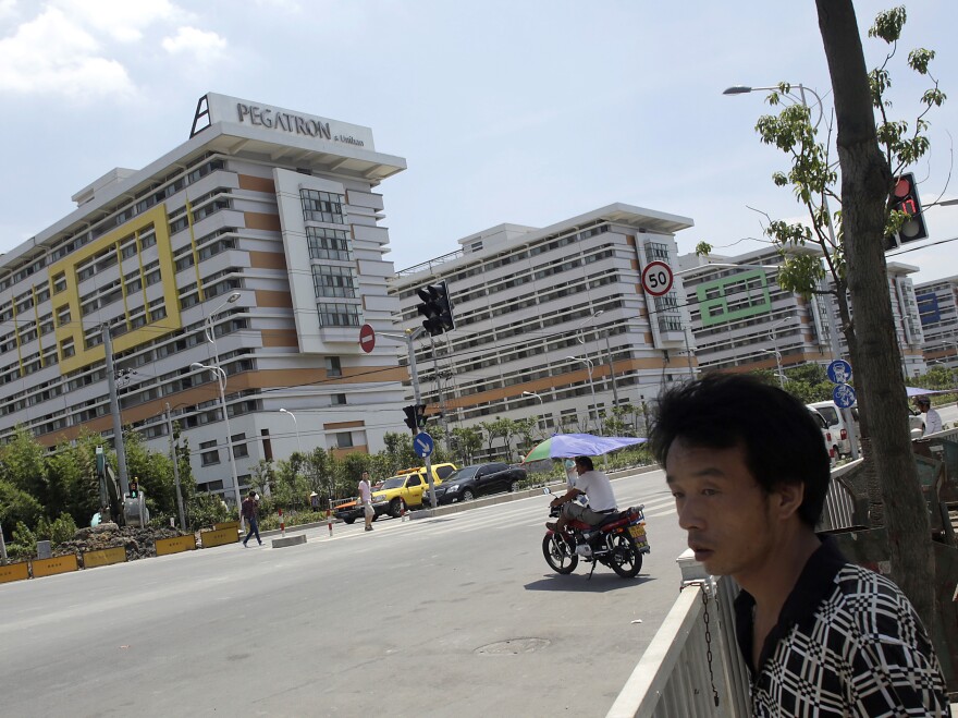 People walk near several buildings of a Pegatron factory in Shanghai, China, in July 2013. Pegatron is a supplier for Apple products.