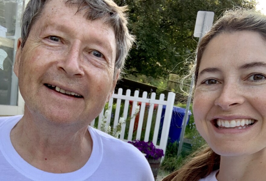 A white man and a younger white woman smile at the camera. They are wearing matching white T-shirts.