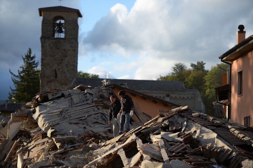 Two men walk on a damaged home after a strong earthquake hit Amatrice, Italy, on Wednesday.