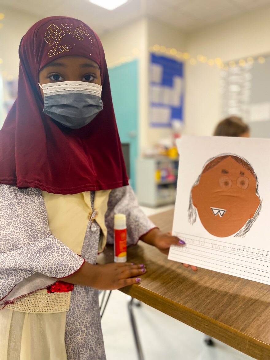 A first grader presents an art and writing project inside of a classroom.