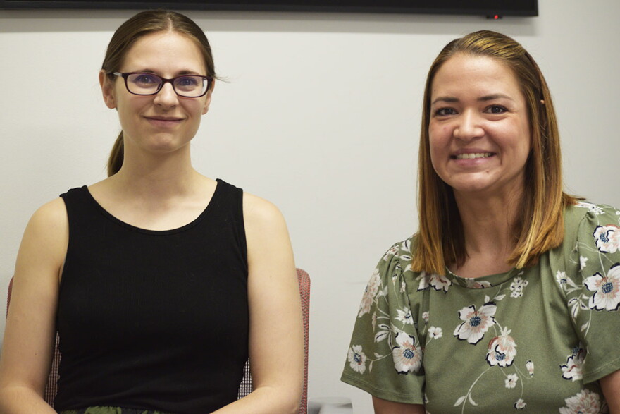 Two women smile for a photo during an interview held in a public radio station studio.  