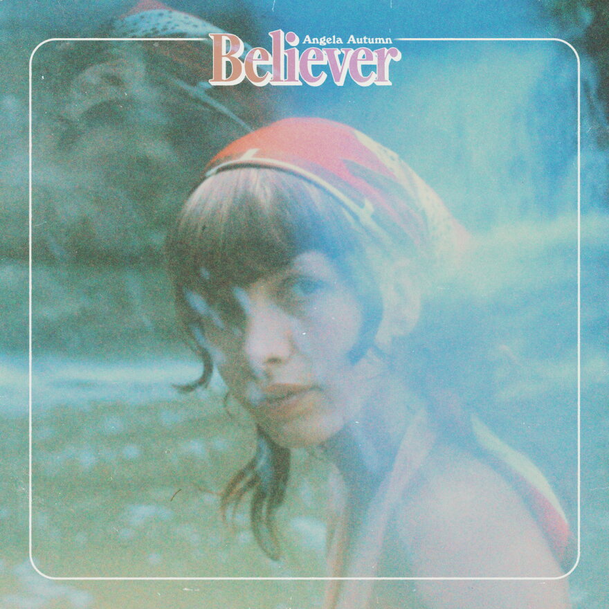 A blue tinged photograph of a woman wearing a bandana in her hair, looking towards the camera.