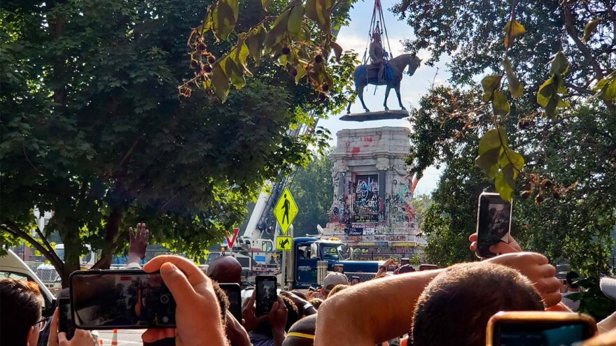 Onlookers crowd around the Lee Monument in Richmond watch as crews remove the statue from the pedestal Wednesday. (Ned Oliver/Virginia Mercury)