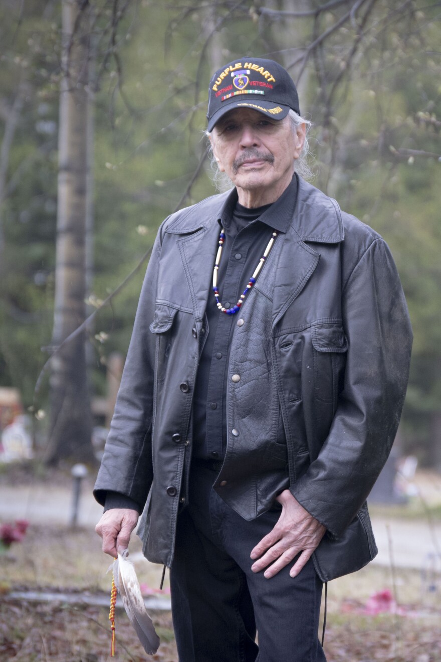 Vietnam veteran Benno Cleveland is Iñupiaq, one of the Indigenous peoples of the Arctic. He holds an eagle feather as he stands in the cemetery where he plans to be buried.