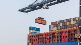 A ship to shore crane in the Port of Hong Kong lifting a shipping container onto a large cargo vessel. Indiana’s Senators are discussing recent tariffs.
