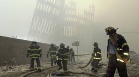 Firefighters work beneath the destroyed mullions, the vertical struts which once faced the soaring outer walls of the World Trade Center towers, after a terrorist attack in New York, Sept. 11, 2001. (Mark Lennihan/AP)