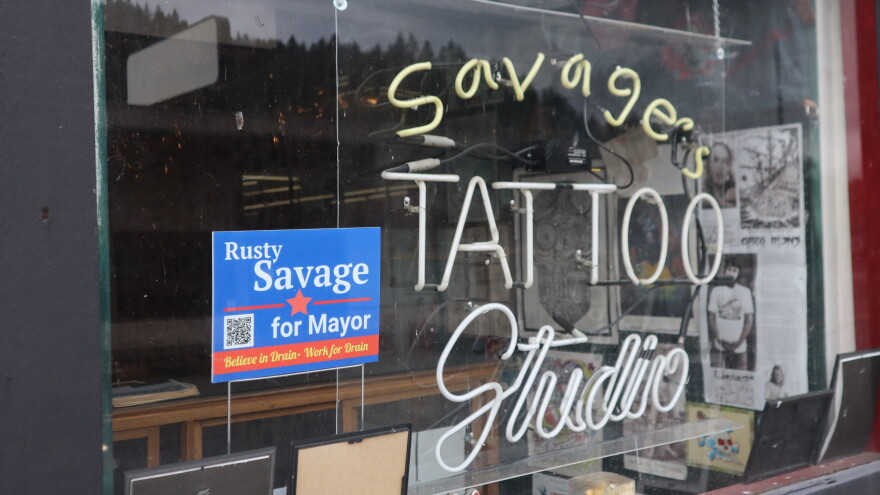 A campaign sign sits in the window of Rusty Savage's tattoo parlor on 1st Street in Drain, Ore. on Oct. 28, 2026.