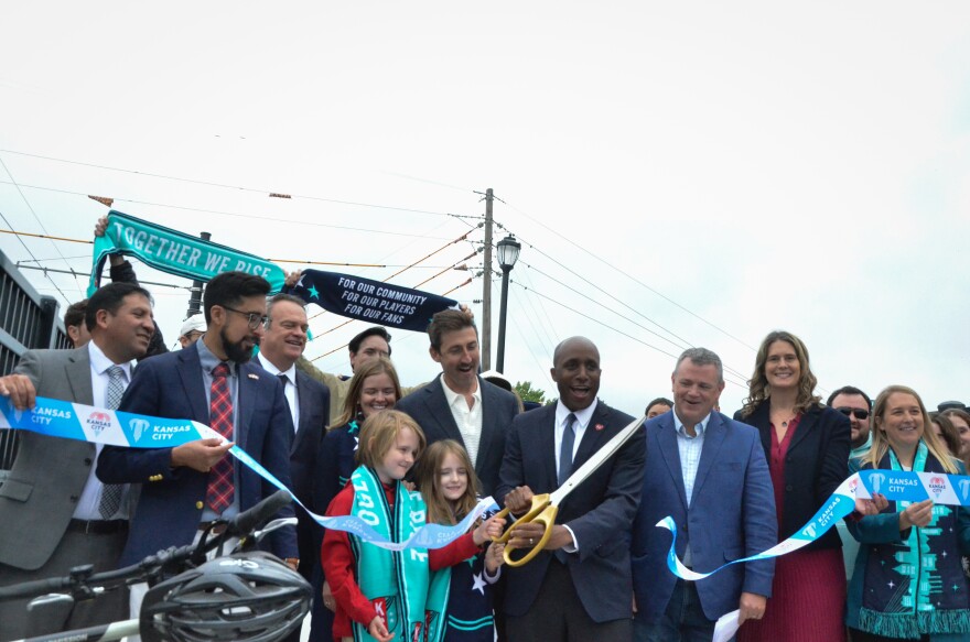 A group of people cut a ribbon and pose for a photo.