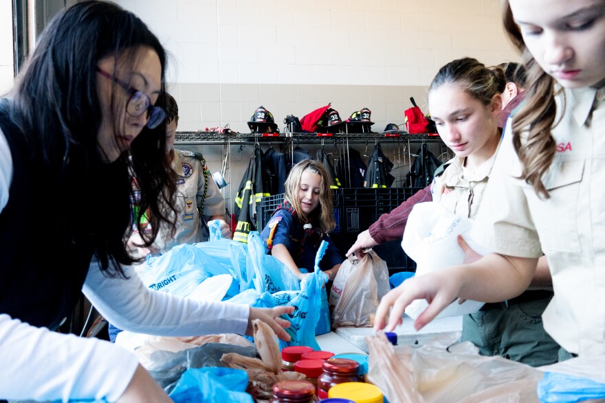 Webelos Scout Renee Brockhaus, 9, sorts through bags of donated food at a table surrounded by other volunteers during the annual Scouting for Food drive.