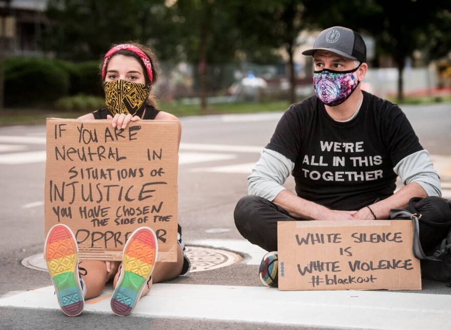 Protesters hold handmade signs while gathering in downtown Raleigh on Tuesday night to protest the death of George Floyd and violence against black Americans.