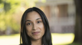 Guadalupe Alvarez, a young woman with long, dark hair, smiles at the camera with crossed arms.