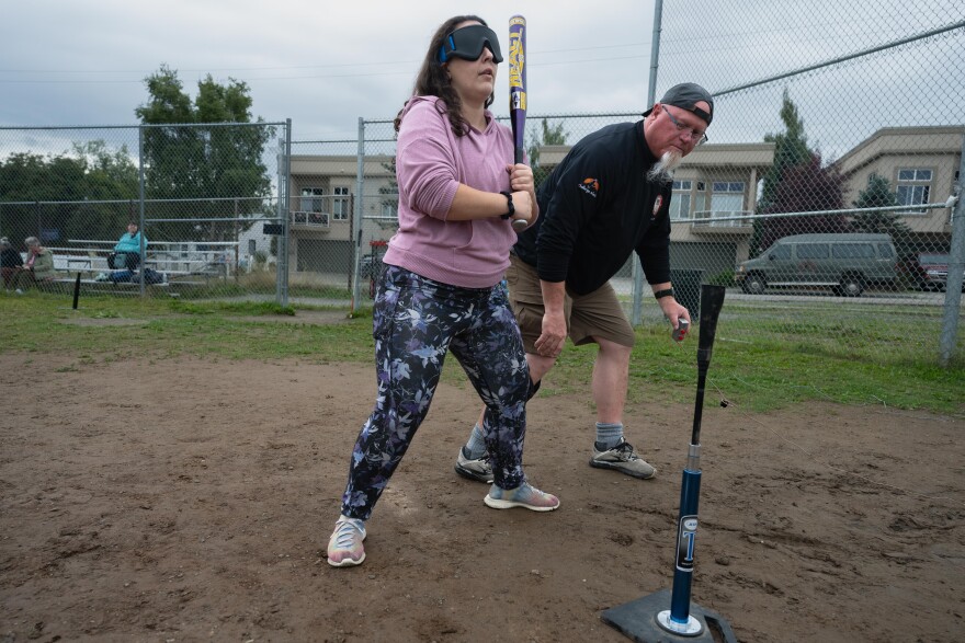 Recreational therapist Jeff Dick, with Challenge Alaska, adjusts Kelsy Tallant's stance during a "beep ball" practice on August 9, 2025