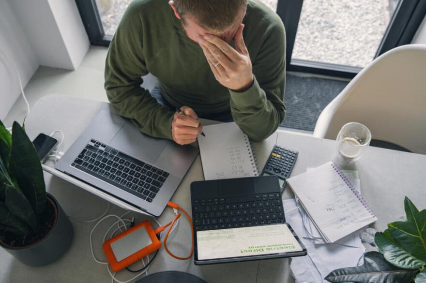 A man, with his hand on his head, takes a break from looking through his home finances and bills. (Justin Paget/Getty Images)
