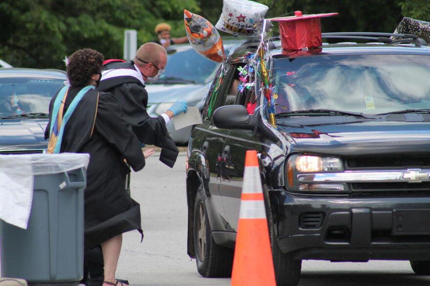 One of Manuel High School's teachers runs up excitedly to a vehicle during the school's drive-thru graduation.