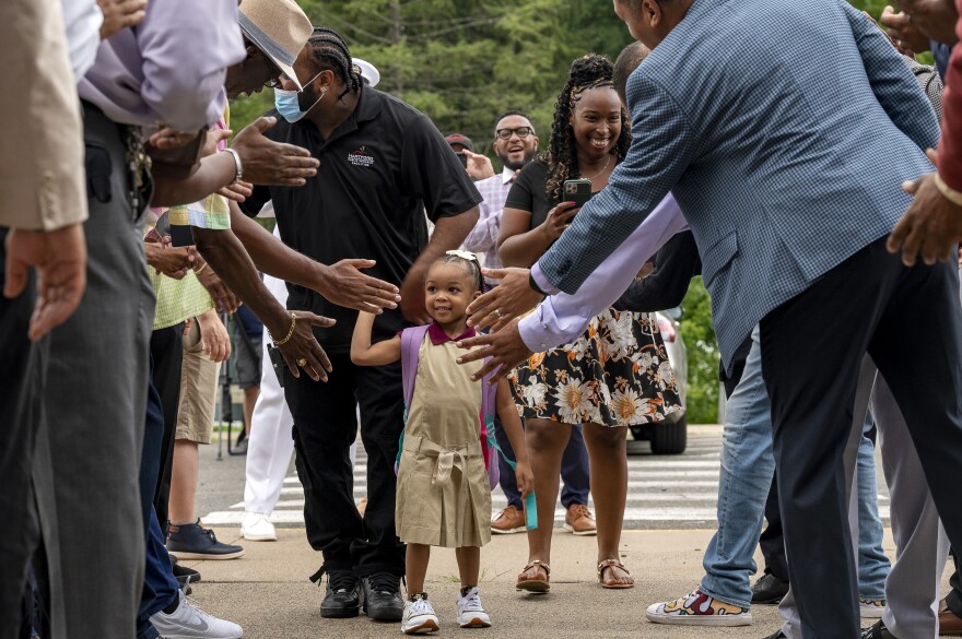 Four year old Jocelyn Wilson parades though a line of high fives on her way to her first day of pre-kindergarten. Her mother Tissa Burrell and dad Jonathan Wilson, head custodian at Rawson, close behind. The students and families of Rawson Elementary School in Hartford are greeted with enthusiasm by members of Calling All Brothers.