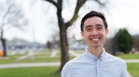 Eric Chung smiles for a photo outside in front of a blurred neighborhood background.
