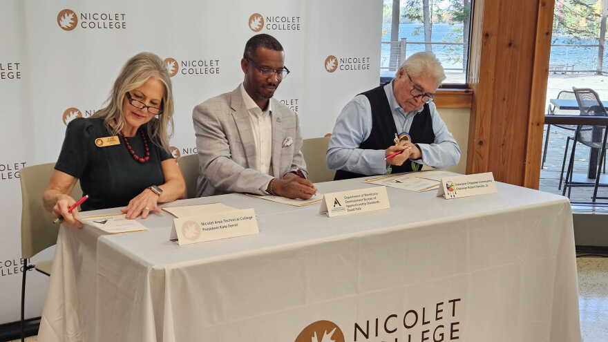 Nicolet College President Kate Ferrell, Director of the Wisconsin Bureau of Apprenticeship Standards David Polk, and Sokaogon Chippewa Community Chairman Robert VanZile sit at a table at the college signing an agreement that will launch a Broadband Service Technician apprenticeship program.