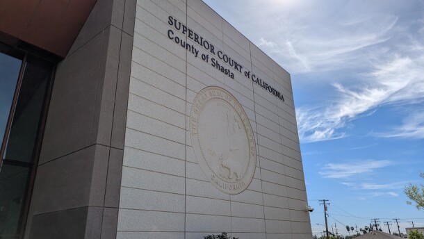 A grey building with a sign that reads, "Superior Court of California, County of Shasta," and the California state seal below it.