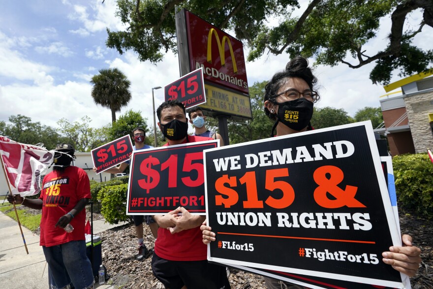 In this file photo, workers and family members take part in a 15-city walkout to demand $15hr wages Wednesday, May 19, 2021, in front of a McDonald's restaurant in Sanford, Fla.