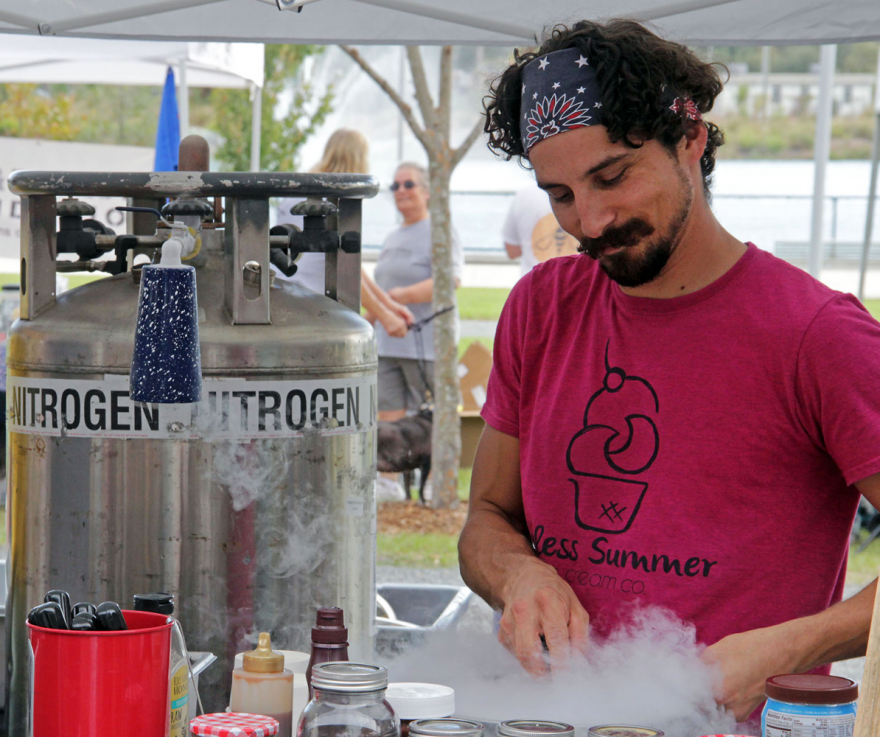 A vendor prepares a bowl of ice cream using liquid nitrogen at the Endless Summer Ice Cream Co. stand at the Pup Ruck 5K Sunday. (Sarah Stanley/WUFT News)