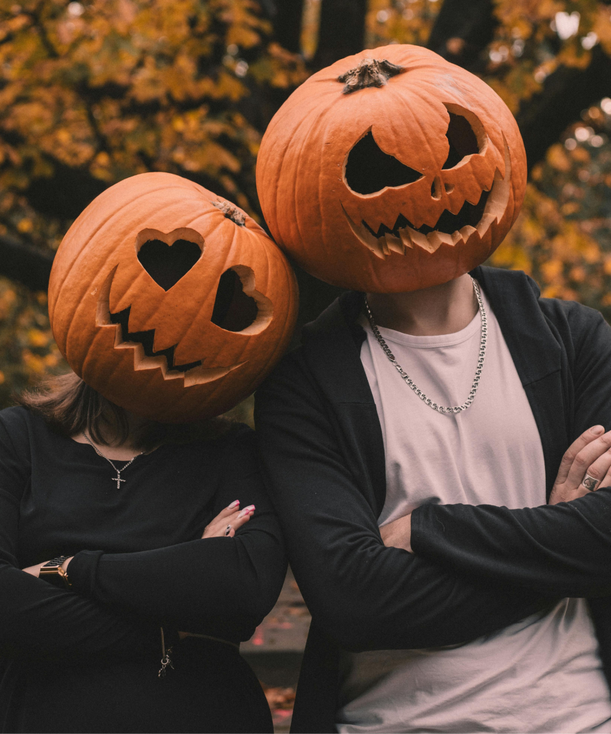 Two people with pumpkins on their heads with pumpkin carvings in a smile
