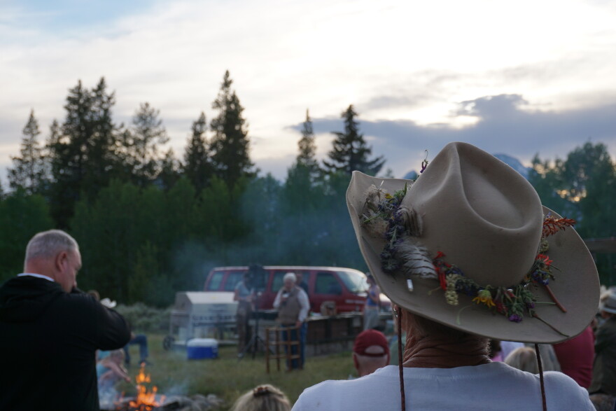 The back of a woman’s head, showing her hat which has wildflowers attached.
