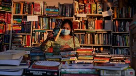 A visitor wearing face mask as a precaution against COVID-19 browse through books. (Mahesh Kumar A./AP)