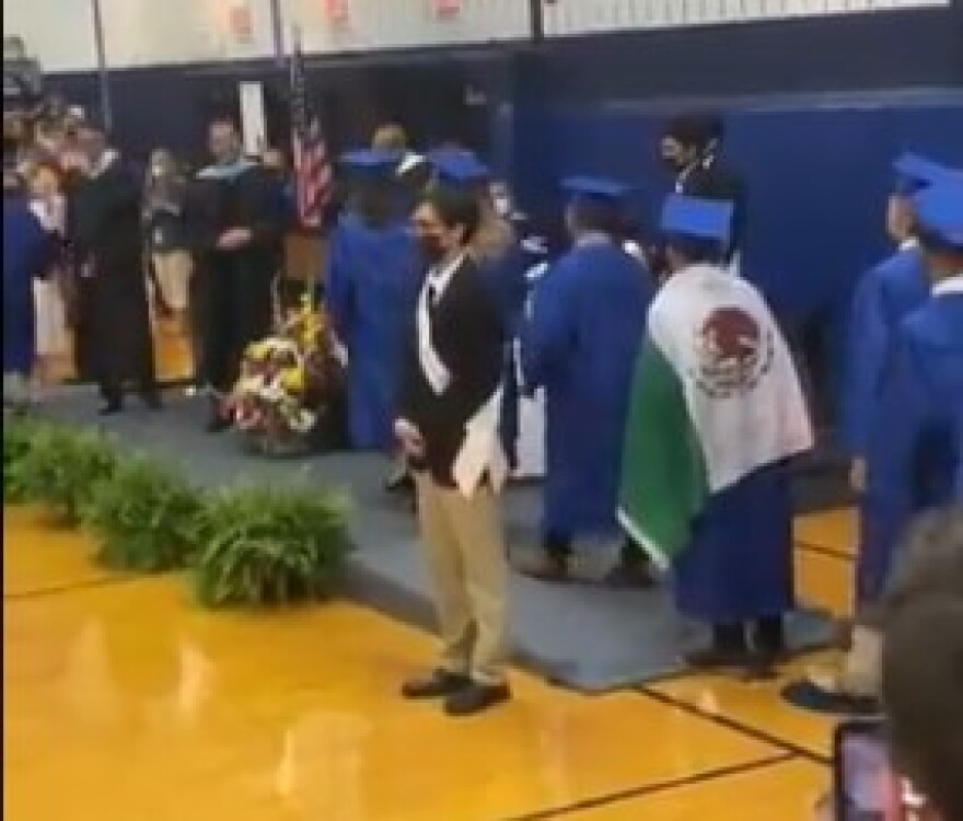 In a video posted on Twitter, a high school student is shown with the Mexican flag draped over his shoulders as he approaches the stage at graduation. A few seconds later, he is not given his diploma.