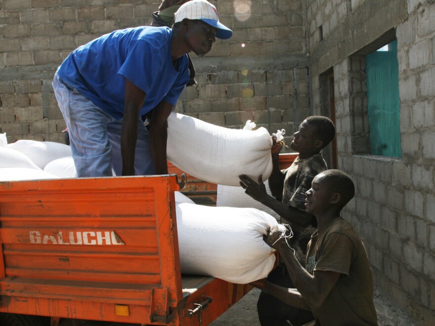 Putting bags of soybeans into makeshift storage at the farm called Rei do Agro. The farm's steel grain bins are still under construction.