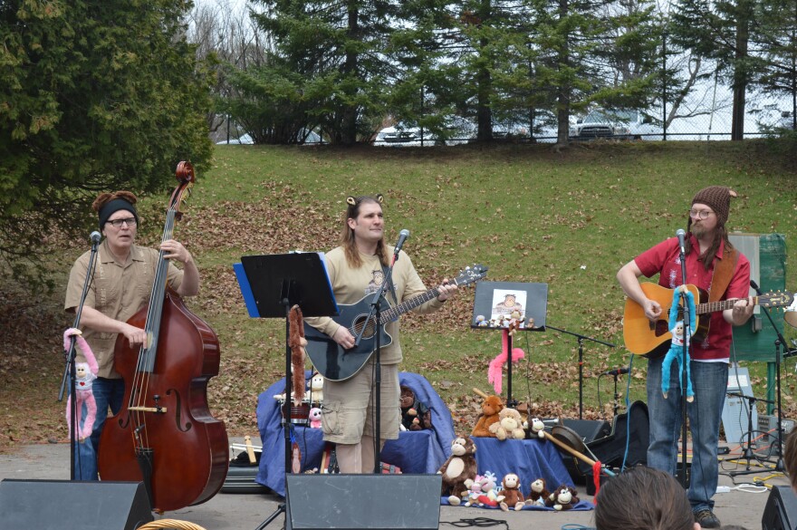 Man playing standup bass and two men playing guitar