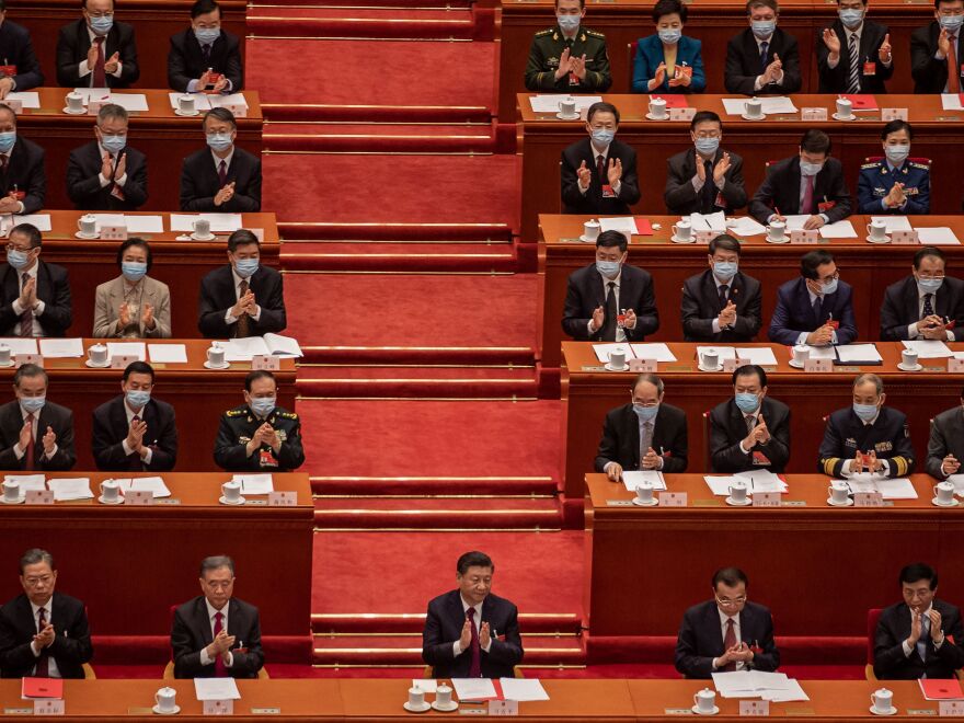 China's President Xi Jinping (C) applauds with other leaders and delegates after they voted on changes to Hong Kong's election system during the closing session of the National People's Congress at the Great Hall of the People in Beijing on March 11, 2021.