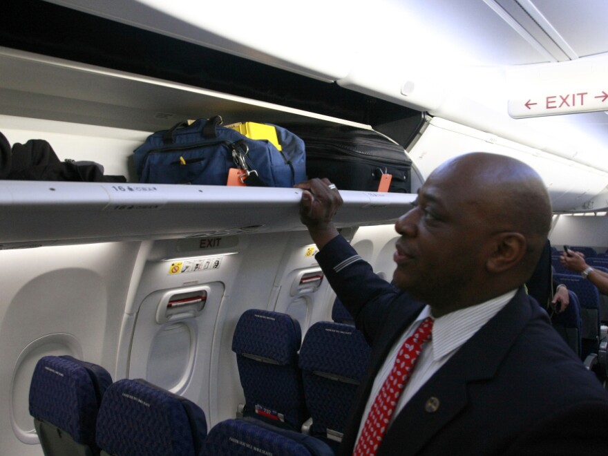 A flight attendant prepares to close a luggage bin on the redesigned 737. Thanks to the bin's new pivoting motion, passengers in the aisle seat will have more headroom.