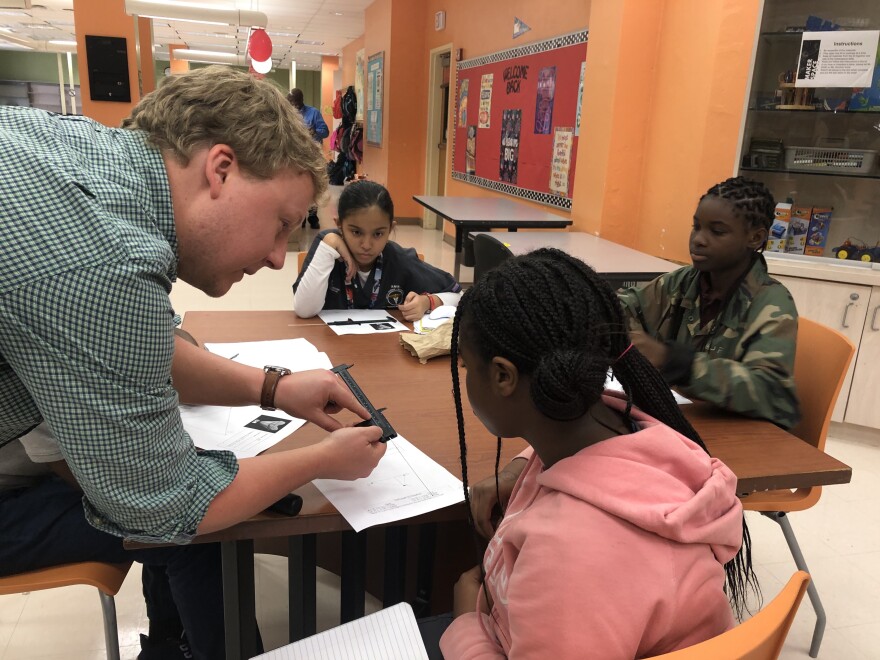 UF doctoral student Sean Moran shows a seventh grader at Roosevelt Middle School in West Palm Beach how to measure and calculate the size of a megalodon tooth.