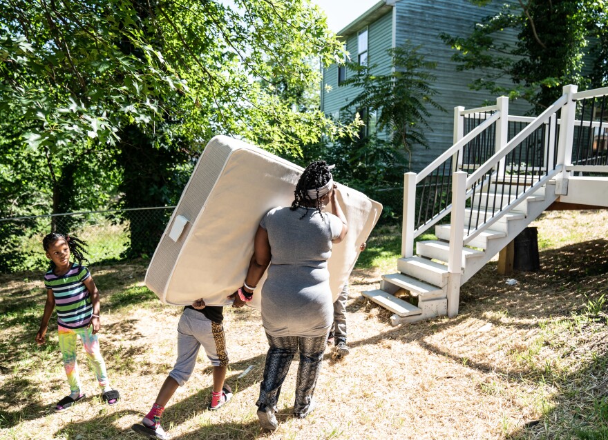 Tasharn and her children move a mattress into their new home. Until recently, the 42-year-old mother of 10 spent her entire life in public or government-subsidized housing.