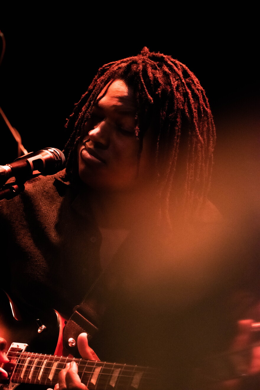 A man singing into a microphone and playing guitar.