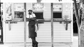 black and white photo of Ricky Moore standing in front of his restaurant