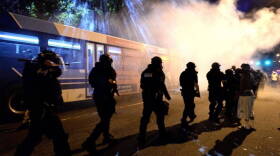 Charlotte-Mecklenburg police officers walk throught a haze of tear gas on Old Condord Rd. in Charlotte on Sept. 20.