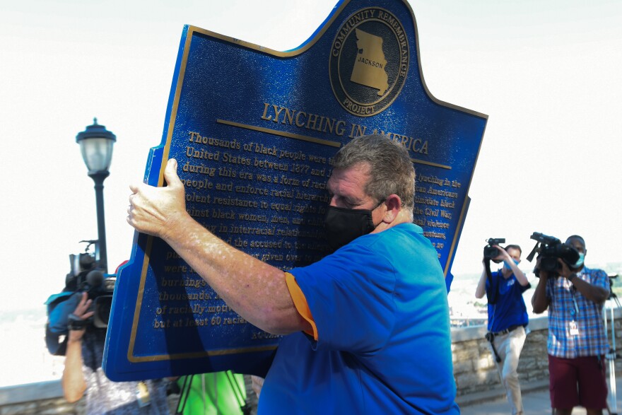 Shaw Ed, a maintenance supervisor with the Kansas City Parks and Recreation Department, carries away the plaque marking the 1882 lynching of Levi Harrington from Case Park on Friday morning.