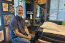 Canyon Webb sitting inside his tattoo shop, Good Neighbor Tattoo.