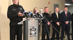 Albany County Sheriff Craig Apple stands at a podium with media microphones, along with other law enforcement officials.